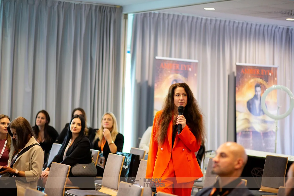 Konferencja Amber Eyes 2025 - prelegentka z mikrofonem i uczestnicy na sali wykładowej